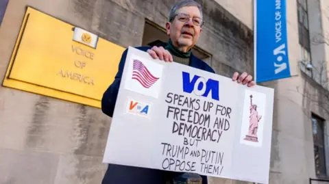 EPA Steve Lodge, whose father Robert Lodge was a correspondent in Voa, standing in front of the organization's headquarters in Washington, DC. Wearing a marine coat, carrying a sign that says: "Voa talks about freedom and democracy, but Trump and Putin opposes them!"