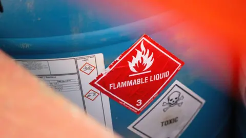 Stock image of a barrel with a sign warning that the contents are flammable.