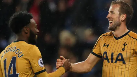 Georges-Kevin Nkoudou shakes hands with Harry Kane as both players are seen in yellow Tottenham Hotspur shirts