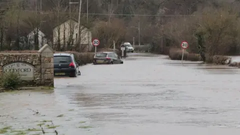Cars half submerged in water on a road in the south west.