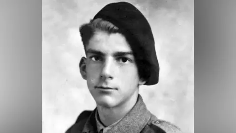 Contributed A black and white image of a young soldier who looks at the camera. He wears a black beret hat drooping over the left side of his head and ear. 