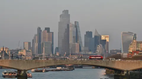 Getty Images Vehicles travelling across Waterloo Bridge with the towers of the City of London seen behind it and the vessels on the River Thames beneath it