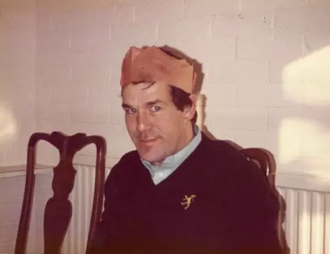 Photograph of Ronnie Lockwood wearing a Christmas cracker hat.