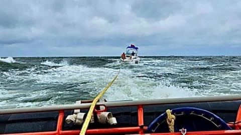 A small boat being towed by Caister Lifeboat in rough seas