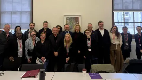 Office of Dr Simon Opher MP Several members of a delegation from the comedy sector stood in a line posing for a photo with minister Ian Murray.