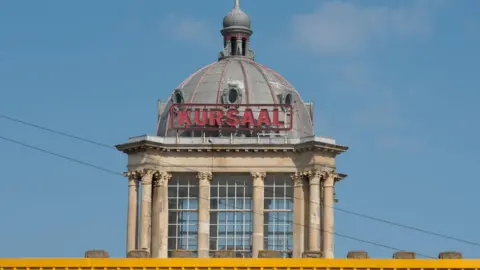 Getty Images The tower of the Kursaal. It has beige columns propping up a silver dome. There are large windows at the centre and a red sign that says "Kursaal" on top.