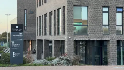 A close up image of Deanery CE Academy with the sign outside