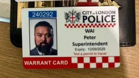 Counter Terrorism Policing A close-up of a City of London Police warrant card with Wai's picture. It reads Wai, Peter, Superintendent, Expiry: 13/09/2029, Not a permit to travel 