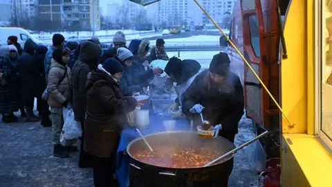 Getty Images Volunteers of the US-based food charity World Central Kitchen distribute hot meal to local residents in a residential area of Kyiv.