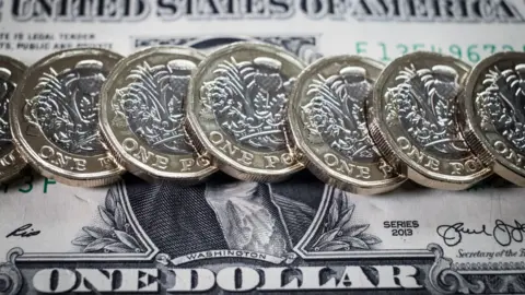 Getty Images Row of new pound coins on one dollar bill