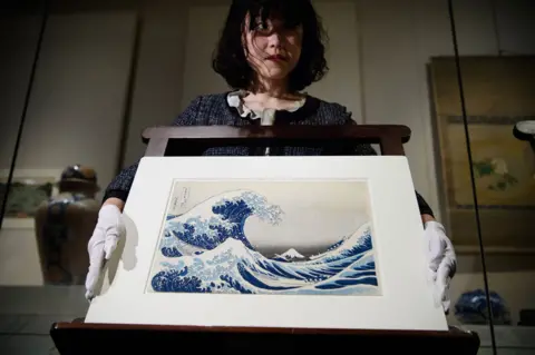 Getty Images A British Museum curator with an early copy of the wood-block print