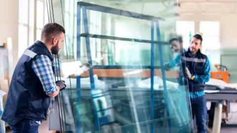 Getty Images Workers moving glass