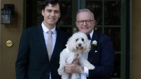 Reuters O primeiro-ministro australiano, Anthony Albanese, está com seu filho Nathan e seu cachorro, o portador do anel Toto - todos voltados para a câmera