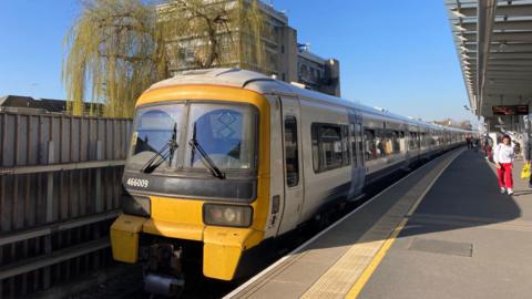 A Southeastern class 466 train in a white livery departs Abbey Wood station