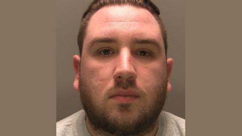 Police image of Reece Doughty with beard and slicked back hair