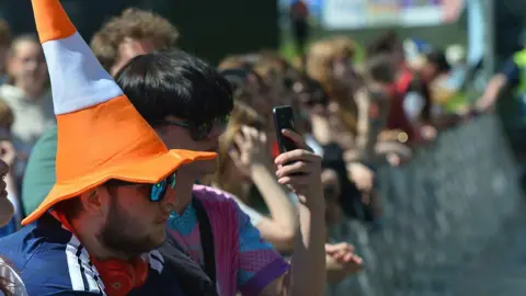 Getty Images A row of fans at TRNSMT, along a barrier. One of them is wearing a novelty hat shaped like a traffic cone