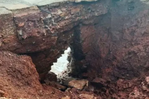 Great Western Railway A large hole in the cliffs beside the Dawlish–Teignmouth railway line, exposing rock and showing the sea through a gap formed after Storm Ingrid.
