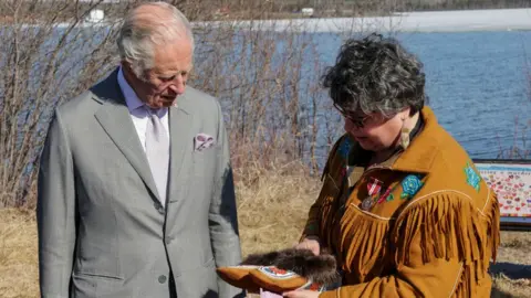 Getty Images A woman shows Prince Charles a traditional Dene shoe, decorated with colourful stitching and a fur trim