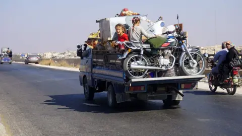 AFP Children ride on the back of a van loaded with possessions as it drives along the Damascus-Aleppo highway in Idlib province (11 September 2018)