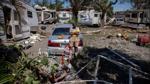 Getty Images Man sits on his damaged car in Fort Myers