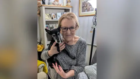 A woman holding a dog in a living room