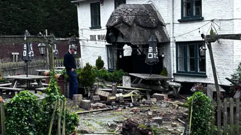 The Woolpack, Sopley A smashed fencing outside a pub, with damage to the furniture and the front of the pub building.