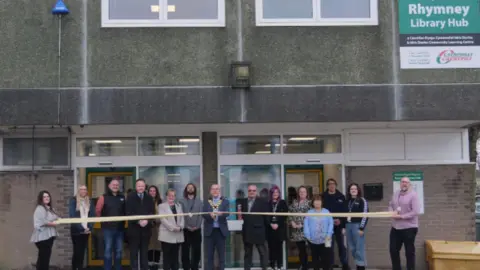 CCBC Rhymney Library reopening as a hub following refurbishments in January 2024. Council members are seen outside ready to cut a ribbon for its reopening.