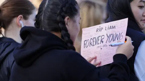 PA Media A fan in Liverpool writing a message for Liam Payne, which reads 