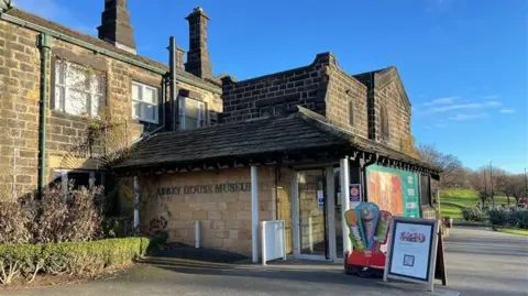 The front entrance of Abbey House Museum, a brown, Victorian style brick building. 