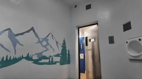 A cell with a mural on the wall of a mountain scene