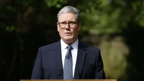 Getty Photos Top Minister Sir Keir Starmer sporting glasses and a suit delivering a speech within the starting up air