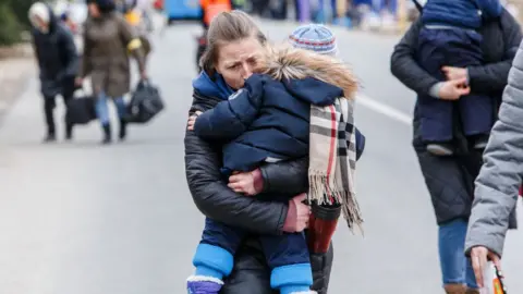 Woman crossing the border between Ukraine and Slovakia carrying a child