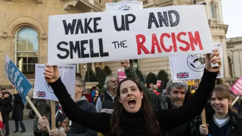 Getty Images Protestors in Hackney including one prominently holding a banner stating: Wake up and smell the racism