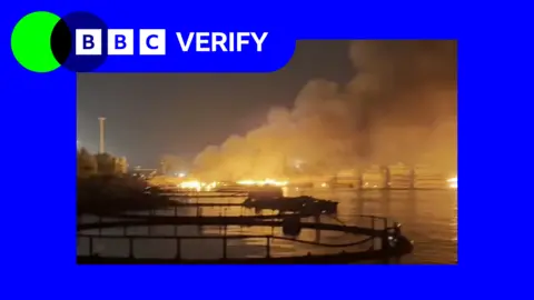an image of a harbour on fire at night in the port city in Iran. the photo is surrounded by BBC Verify blue and green branding