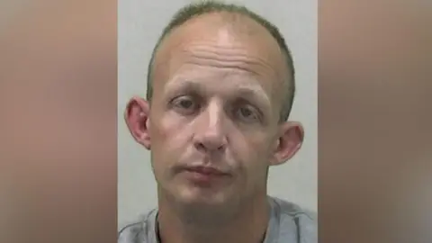 Northumbria Police Mugshot of Hall. He is clean shaven and balding with short fair hair, a drooped expression on his face and large ears.