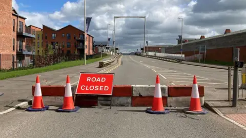 BBC The High Orchard bridge in Gloucester with "road closed" signs and traffic cones in the foreground