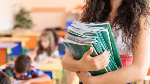 Getty Images Teacher carrying books