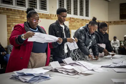 A woman holding a ballot paper as Independent Electoral Commission (IEC) count ballots at the Craighall Primary School polling station in Johannesburg on May 29, 2024, during South Africa's general election. 