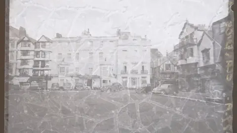 South West Heritage Trust A faded negative of the Royal Clarence Hotel which is showing signs of damage across the image. There is writing in yellow running along the side of the negative.

