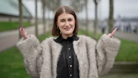 BBC's Eve Beattie looks at the camera with her hands up in the air and a confused expression