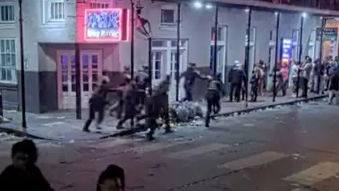 Police run down the street in New Orleans