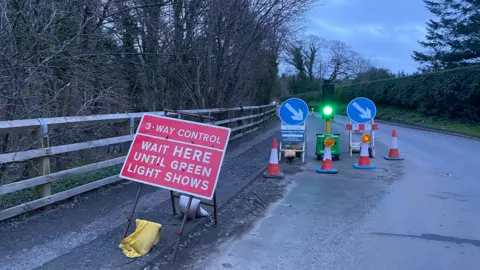 Traffic signs on a country road on a grey evening, advising drivers of a 3-way control