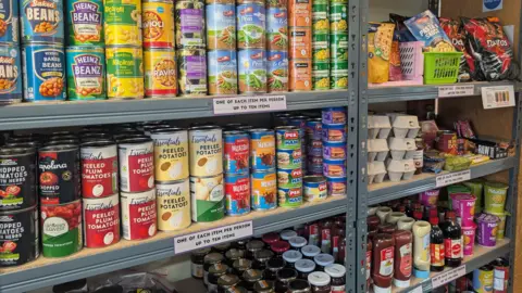 Tara Dolby/BBC Rows of tins, jars, bottles and eggs arranged on metal shelving