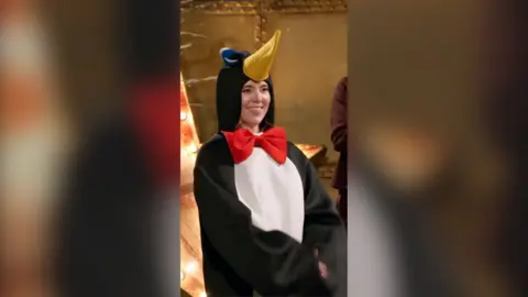 A woman smiles in a penguin outfit