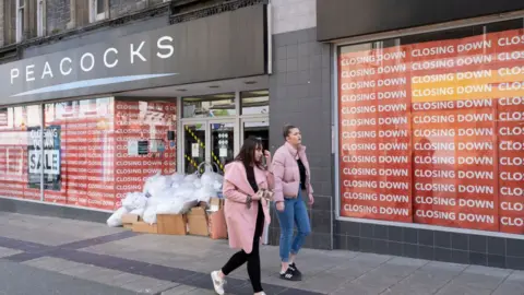 Getty Images Two young women walk past a closed Peacocks clothing store on Bangor High Street