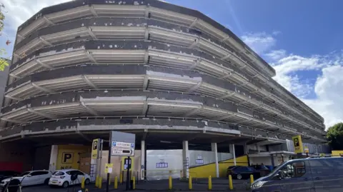 A multi-storey car park with large sitex metal boards on the entrances