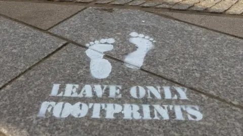 North Somerset Council A stencilled message on a pavement reading "leave only footprints" with a footprint stencil