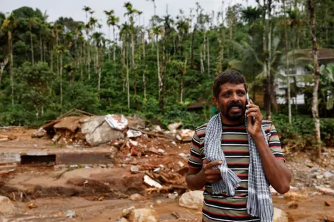 Reuters A man cries as he speaks to relatives after his home and auto rickshaw was destroyed after multiple landslides hit the hills in Wayanad