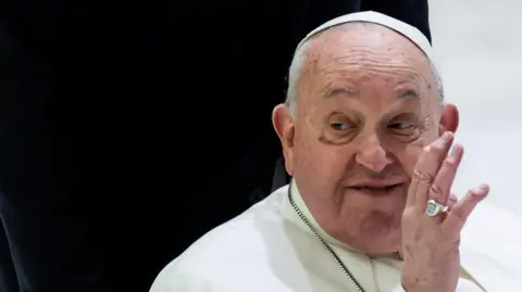 Pope Francis waving his left hand against a black and white background