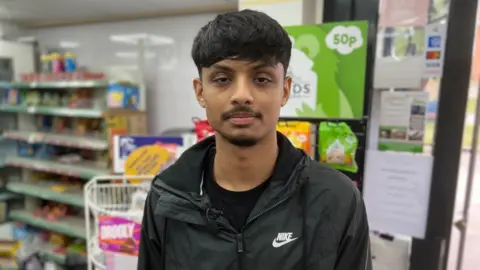 Vyom Shah, Ketan's son, looking at the camera in a shop.